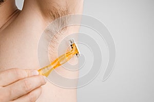 Close up man shaves hairy armpits with a yellow razor. Unshaved armpits or underarm. Depilation and hair remove