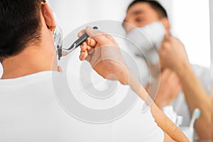 Close up of man shaving beard with razor blade