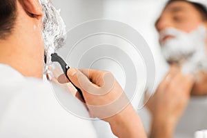 Close up of man shaving beard with razor blade