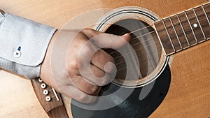 Close-up of a man in shirt playing fingerstyle guitar photo