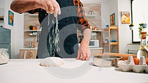 Close up of man sieving flour on bread dough