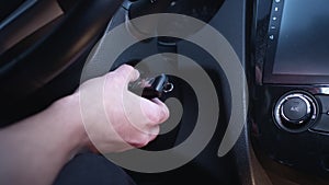Close-up of a man starts the car. The driver turns the key in the ignition by hand. Car dashboard. The beginning of the