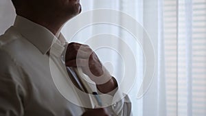 Close-up of a man straightens his tie