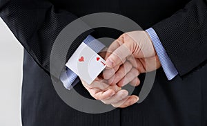 Close up man suit holds ace card behind his back