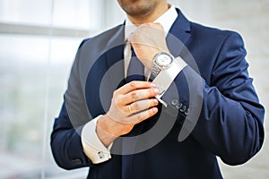 Close-up of man in suit with watch on his hand fixing his cufflink. groom bow tie cufflinks