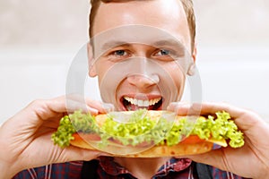 Close up man taking bite of sandwich