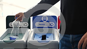 Close-up of man throwing garbage into sorting bins. Media. Man throws garbage into colored bins for sorting. Sorting