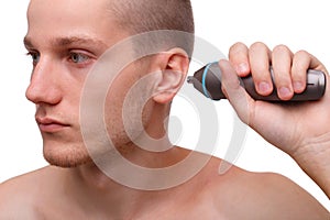 Close-up of a man with a trimmer near his ear isolated on white background