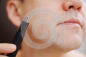 close-up. a man with trimmers for cutting hair in nose and ears.