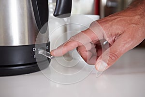 Close Up Of Man Turning On Switch To Boil Kettle