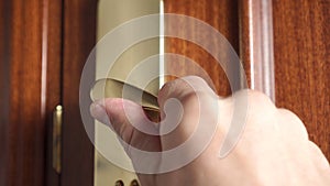 Close-up of a man turns a bronze doorknob, unlocks the lock