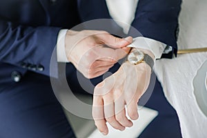 Close-up of a man in a tux fixing his cufflink. groom bow tie cufflinks. Groom adjusts cufflinks, groom in a blue suit straightens