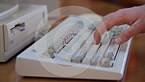 Close-up of man typing on retro keyboard. Media. Man uses old computer, typing on old keyboard. Old computer equipment