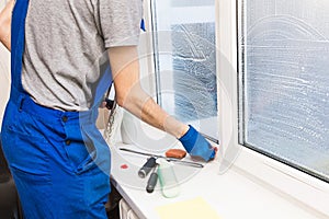 Z muž v jednotný modrý rukavice umýva okna stierač. profesionálne čistenie služba 
