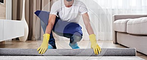 Close up of man unrolling carpet. Cleaning service concept