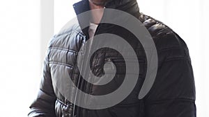 Close up of man unzipping his black jacket at home