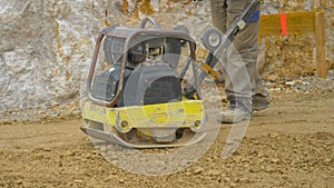 CLOSE UP Man uses manual levelling machine to prepare ground for mortar pouring
