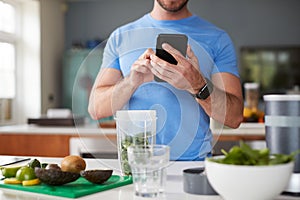 Close Up Of Man Using Fitness Tracker To Count Calories For Post Workout Juice Drink He Is Making