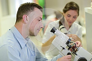 close up man using microscope
