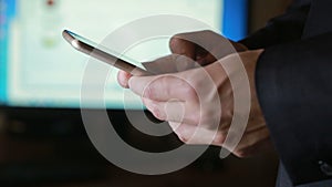 Close up of a man using mobile smart phone. the background monitor