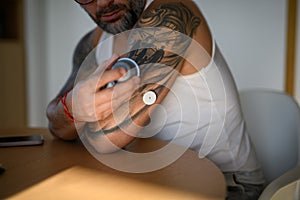 Close up of man using sensor applicator to insert the CGM sensor into his arm.