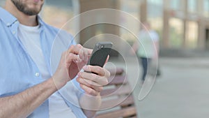 Close Up of Man Using Smartphone while Sitting Outdoor on Bench