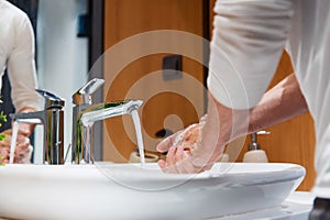 Close up of man washing hands with soap under running water