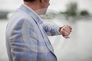 Close-up man with watch on a hand. Businessman checking time on a blurred city background. Business concept. Copy space.