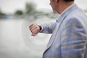 Close-up man with watch on a hand. Businessman checking time on a blurred city background. Business concept. Copy space.