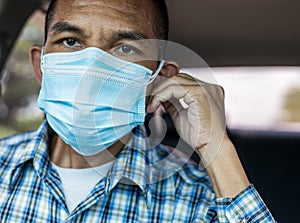 Close-up of a man wearing a double-layered blue mask inside the car photo