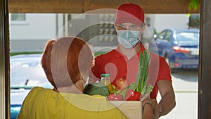 CLOSE UP: Man wearing facemask brings fresh organic produce to senior lady.