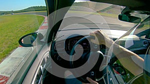CLOSE UP: Man wearing a helmet races his fast car along the fun racetrack.