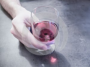 Close up of a man white hand holding a glass of porto wine. Alcoholism is dangerous