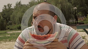 Close-up of a man who enjoys eating a juicy watermelon while sitting outside