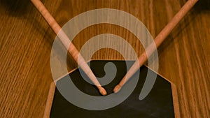 Close up of a man or woman practicing on a drum pad with drumsticks on wooden table background. Concept. A person is