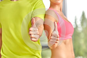Close up of man and woman showing thumbs up in gym