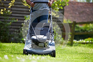 Close Up Of Man Working In Garden Cutting Grass With Mower