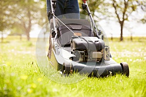 Close Up Of Man Working In Garden Cutting Grass With Mower