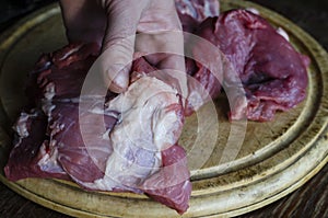 Close-up of a man's bloody hand with a piece of raw meat. An adu