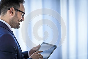 Close-up on a manager holding digital tablet standing in the office. concept of digital age. Businessman typing on the tablet