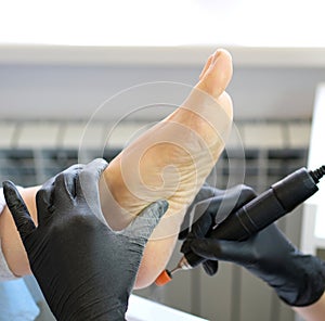 Close up of manicurist hand cutting dry skin on womans toes using metal nippers. Procedure of pedicure in beauty salon.