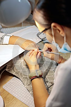 Close-up of manicurist removing cuticles in nail salon photo