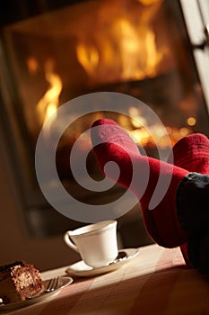 Close Up Of Mans Feet Relaxing By Cosy Log Fire photo