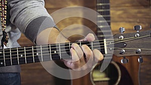 Close up mans hand playing chords on acoustic guitar slow motion