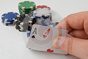 Close-up of mans hand showing his cards with two aces while playing poker. Concept of gambling