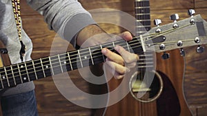 Close up mans hand taking chords on acoustic guitar slow motion