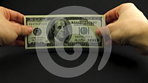 Close-up of mans hands with a bunch of money, american dollars on black background