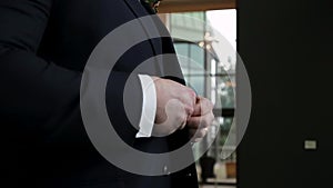 Close up of a mans hands buttoning up a suit jacket on wedding day. HD 24FPS.