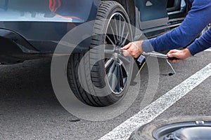 Close up mans hands changing a wheel using screwdriver. Replacing winter and summer tires. Seasonal tire replacement concept.