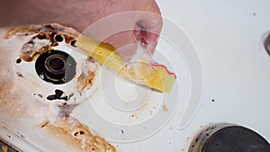 Close-up of a mans hands cleaning the surface of a modern gas stove in the kitchen with a sponge. Washing and cleaning wall tile